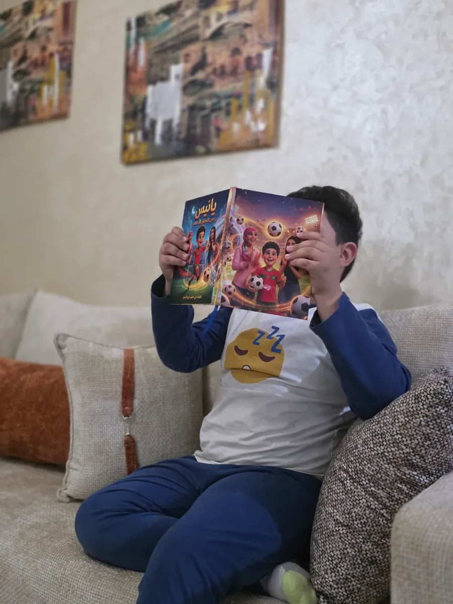 Un enfant assis sur le canapé, cachant son visage derrière son livre personnalisé